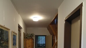 A narrow hallway with wooden doors and a tiled floor.