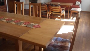 A dining area with a wooden table and chairs, a fireplace, a sofa, and a painting on the wall.