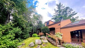 A two-story house with a wooden deck and a stone staircase leading to the entrance. - O42 Renovated with high class upgrades! Ski access, boot warmer, ski rack, yard, AC, dog friendly! (Bretton Woods)