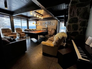 A cozy room with a pool table, comfortable seating, a piano, and a stone wall. - RL Breathtaking views, private mountain retreat. Hot Tub, Dog Friendly, great location! (Dalton)