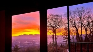 Una habitación con un ventanal grande que da a un paisaje nevado y un atardecer.