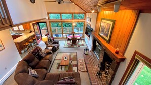 A cozy living room with a fireplace, a large window overlooking a deck, and a comfortable seating area.
