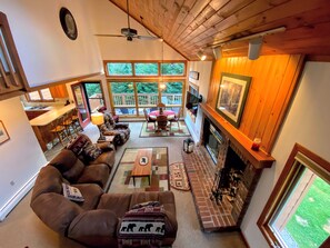 Una sala de estar acogedora con chimenea, un ventanal con vistas a una terraza y un espacio de descanso cómodo.