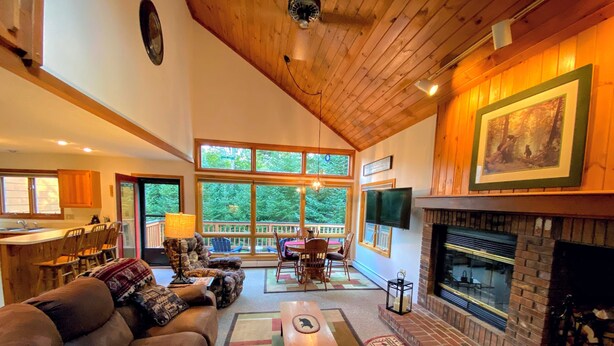 A spacious living room with a fireplace, large windows, and a cozy seating area.