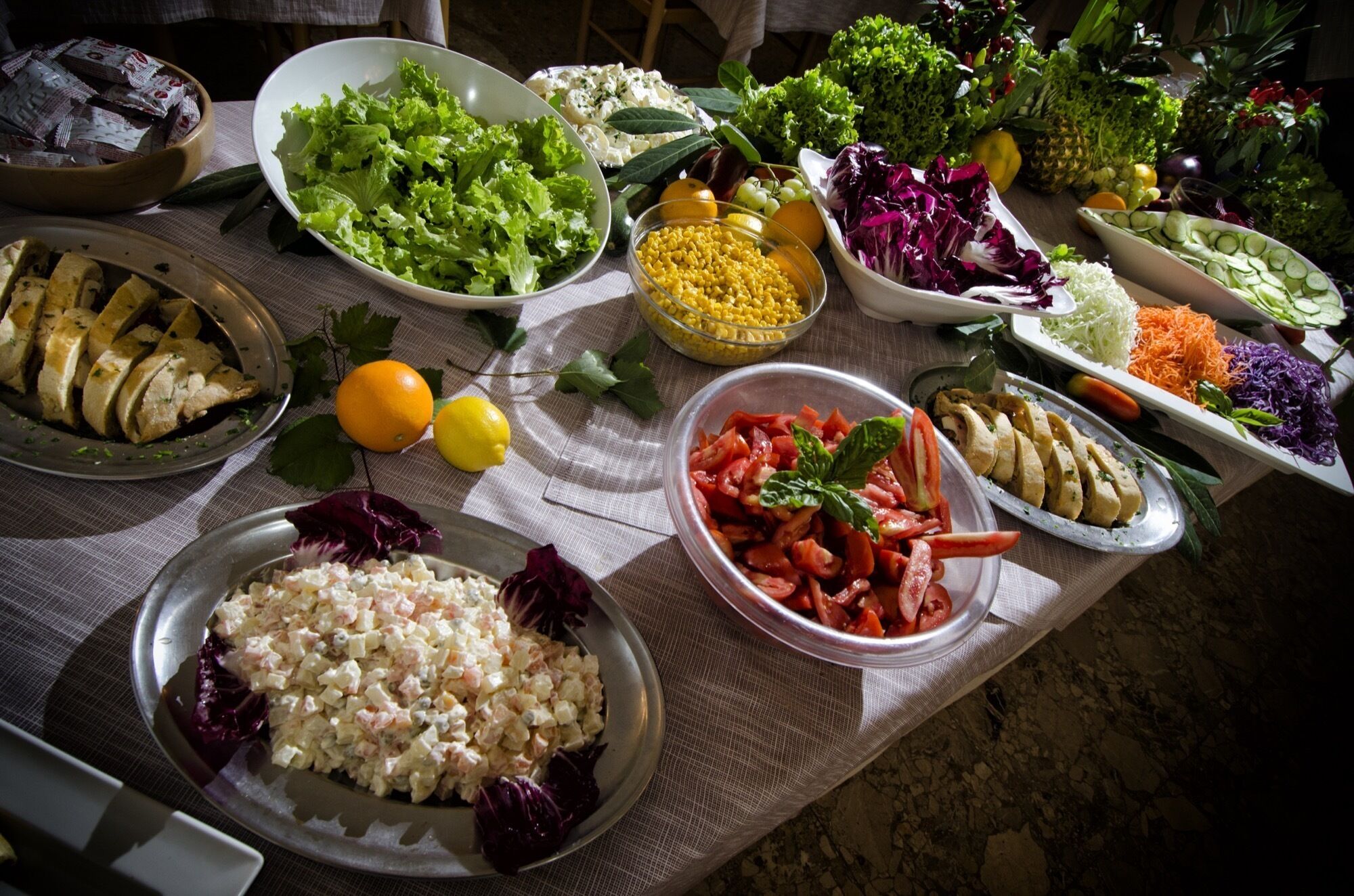 Una mesa con diversos alimentos, como ensaladas, frutas y verduras.