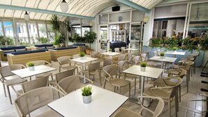 A restaurant with outdoor seating, including tables and chairs, and a variety of potted plants.
