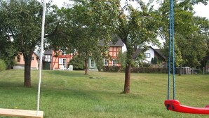 A grassy outdoor area with a swing set and a tree. - House Froschkönig directly on the Weser (Hann. Münden)