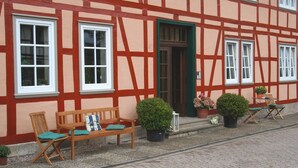 A traditional half-timbered building with a wooden bench and potted plants outside. - House Froschkönig directly on the Weser (Hann. Münden)