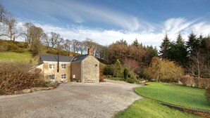 A stone house with a gravel driveway and a well-maintained lawn. - Stunning 3-bed House in a Private Hidden Valley (Denbigh)
