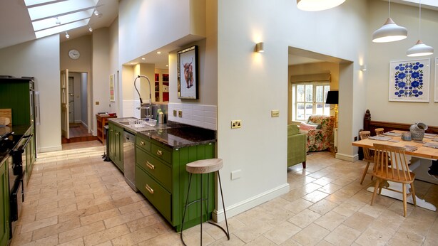 A spacious kitchen with green cabinets, a central island, and pendant lighting. - Stunning 3-bed House in a Private Hidden Valley (Denbigh)