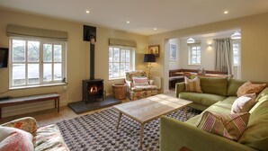 A cozy living room with a fireplace, comfortable seating, and large windows. - Stunning 3-bed House in a Private Hidden Valley (Denbigh)