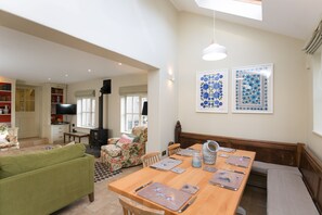A spacious living area with a dining table, sofas, and a television. - Stunning 3-bed House in a Private Hidden Valley (Denbigh)