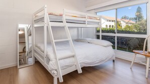 Een slaapkamer met een stapelbed en uitzicht op een huis en bomen.