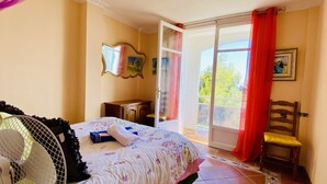 A bedroom with a bed, a nightstand, a chair, a fan, and a sliding glass door leading to a balcony. - Provenc  beach house, breathtaking sea views pool , 5mn walk to beach  (Ensues la redonne)