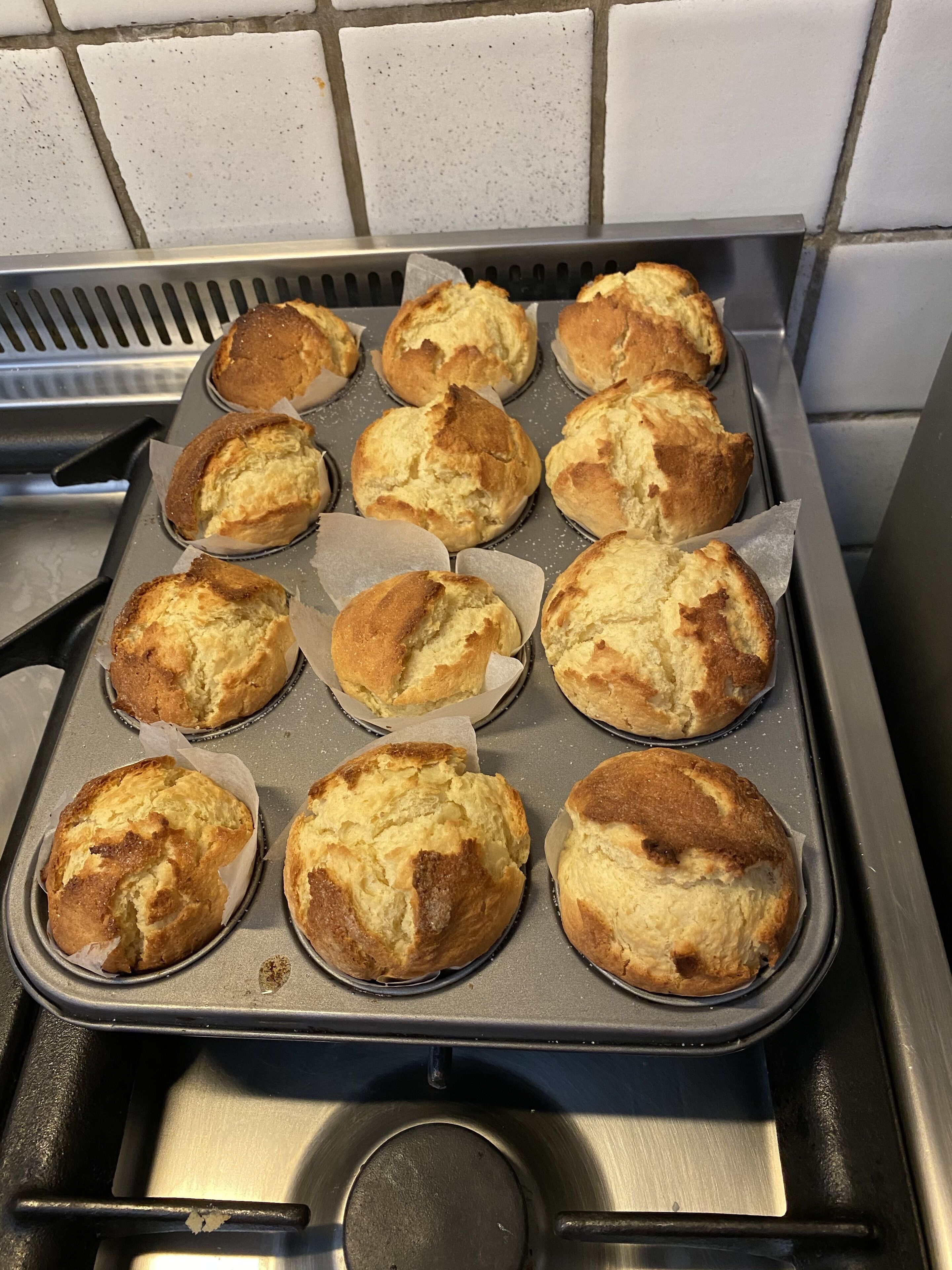 Una bandeja para muffins con productos horneados sobre una cocina.