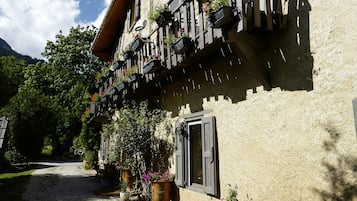 Un edificio con fachada rústica, varios balcones con jardineras y un camino de grava que conduce a la entrada.