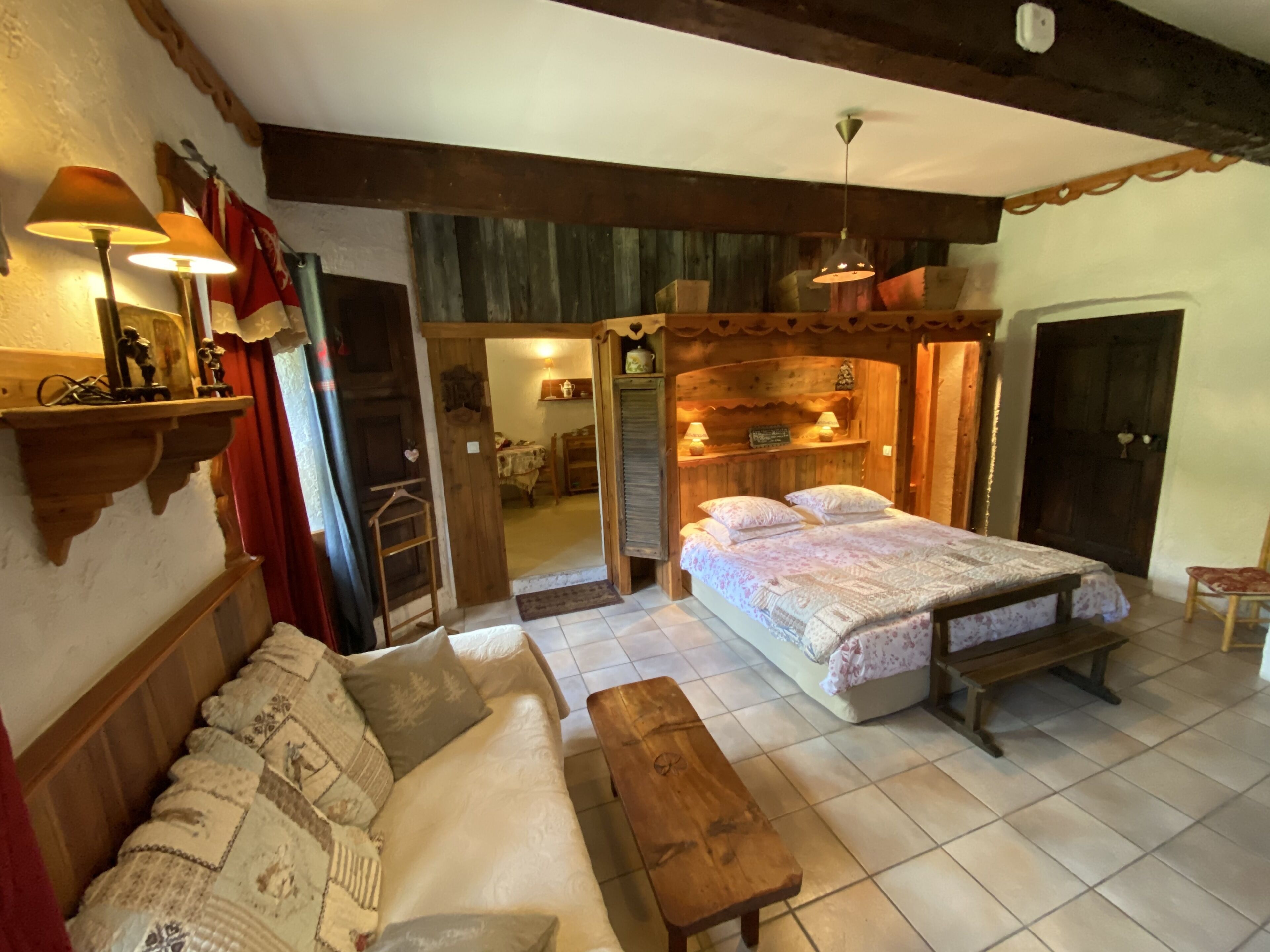 A cozy bedroom with a large bed, a wooden bench, a sofa, and a wooden headboard.