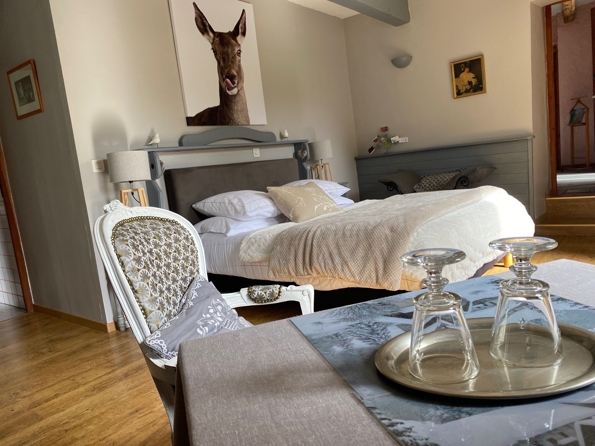 A neatly arranged bedroom with a bed, bedside table, and a painting of a deer on the wall.