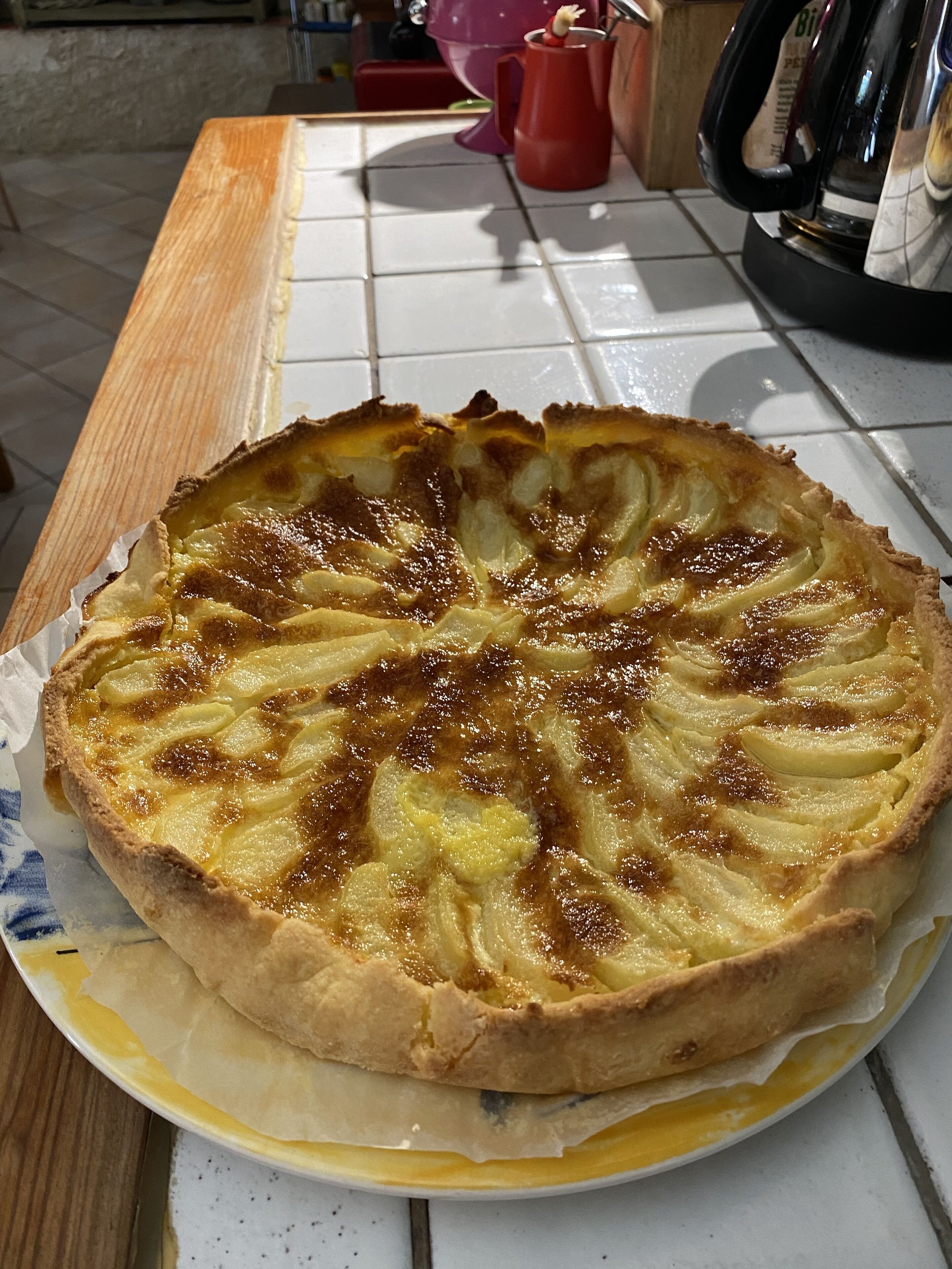 Una tarta redonda con cobertura enrejada, sobre un plato en una encimera de cocina.