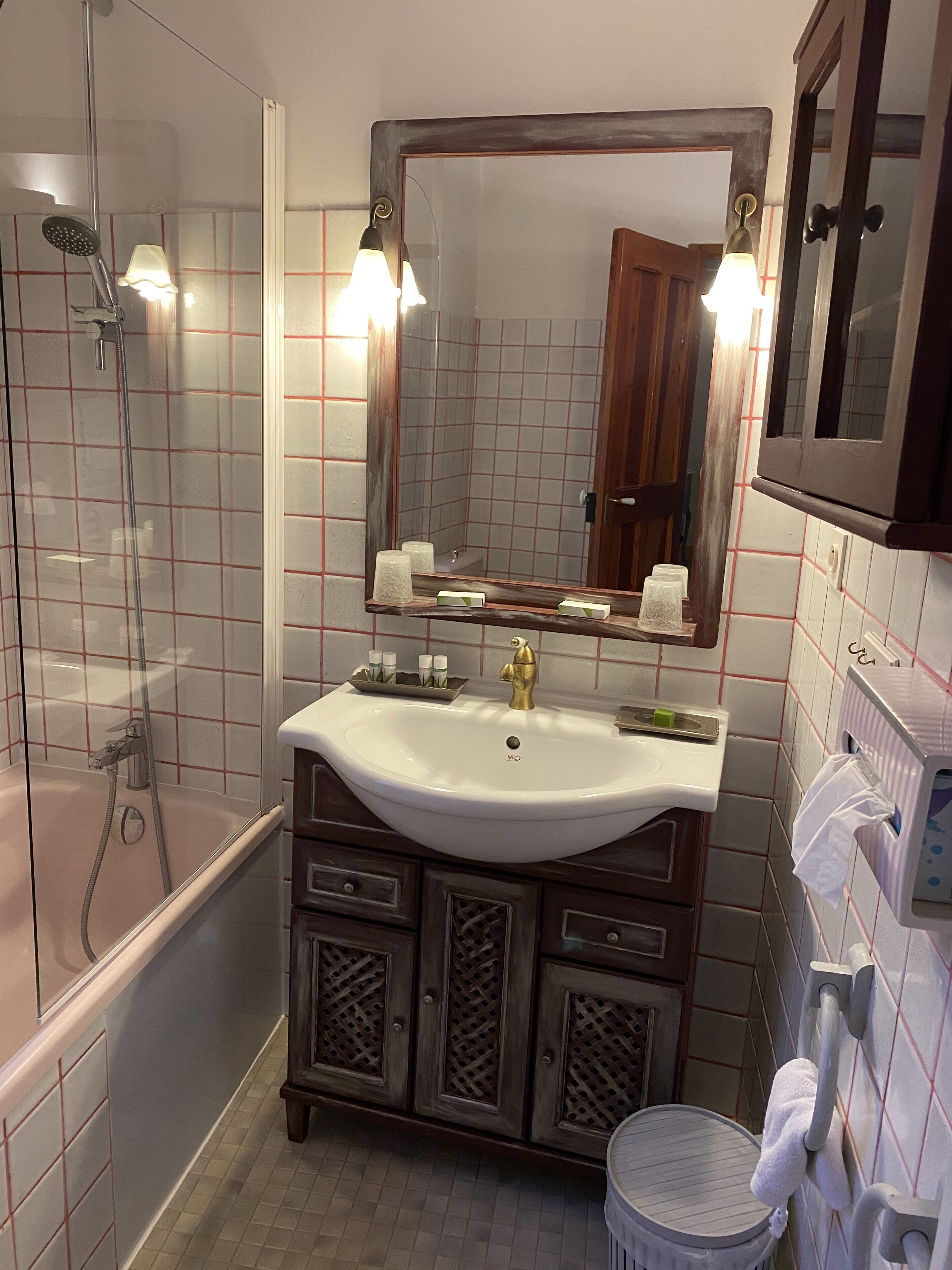 A bathroom with a white sink, a mirror, a shower, and a toilet.