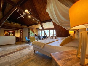 A spacious room with a large bed, a wooden ceiling, and a view of the outdoors. - Maison d'hôtes les Méans (Meolans-Revel)