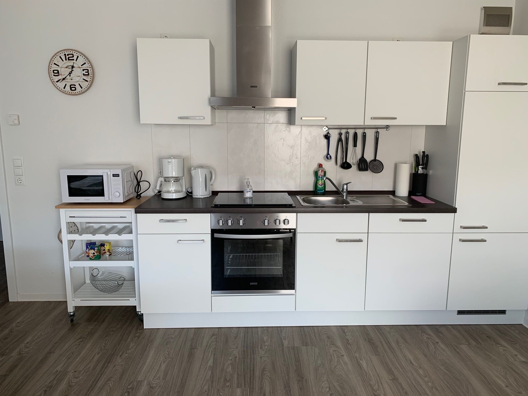 A modern kitchen with white cabinetry, a built-in oven, a coffee maker, and a microwave.