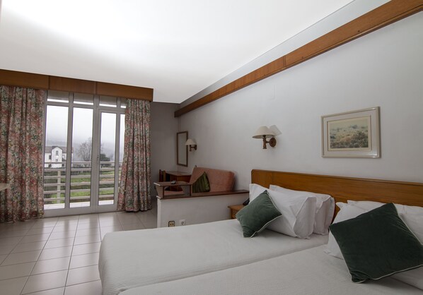 A hotel room with a bed, a desk, and a view of the outside.