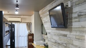 A modern kitchen with a wooden backsplash, a built-in TV, and a wooden countertop. - Oyado Kinokuniya Shinchi Machi (Nagasaki)