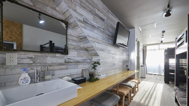 A modern bathroom with a wooden vanity, a large mirror, and a built-in sink. - Oyado Kinokuniya Shinchi Machi (Nagasaki)