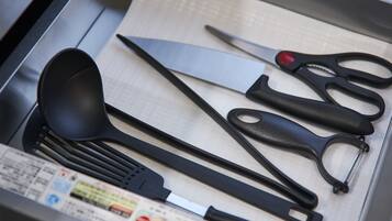 Un cajón con utensilios de cocina, como una espátula, un cuchillo grande y un par de tijeras.