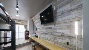 A modern kitchen with a wooden backsplash, a built-in TV, and a long countertop with bar stools. - Oyado Kinokuniya Shinchi Machi (Nagasaki)