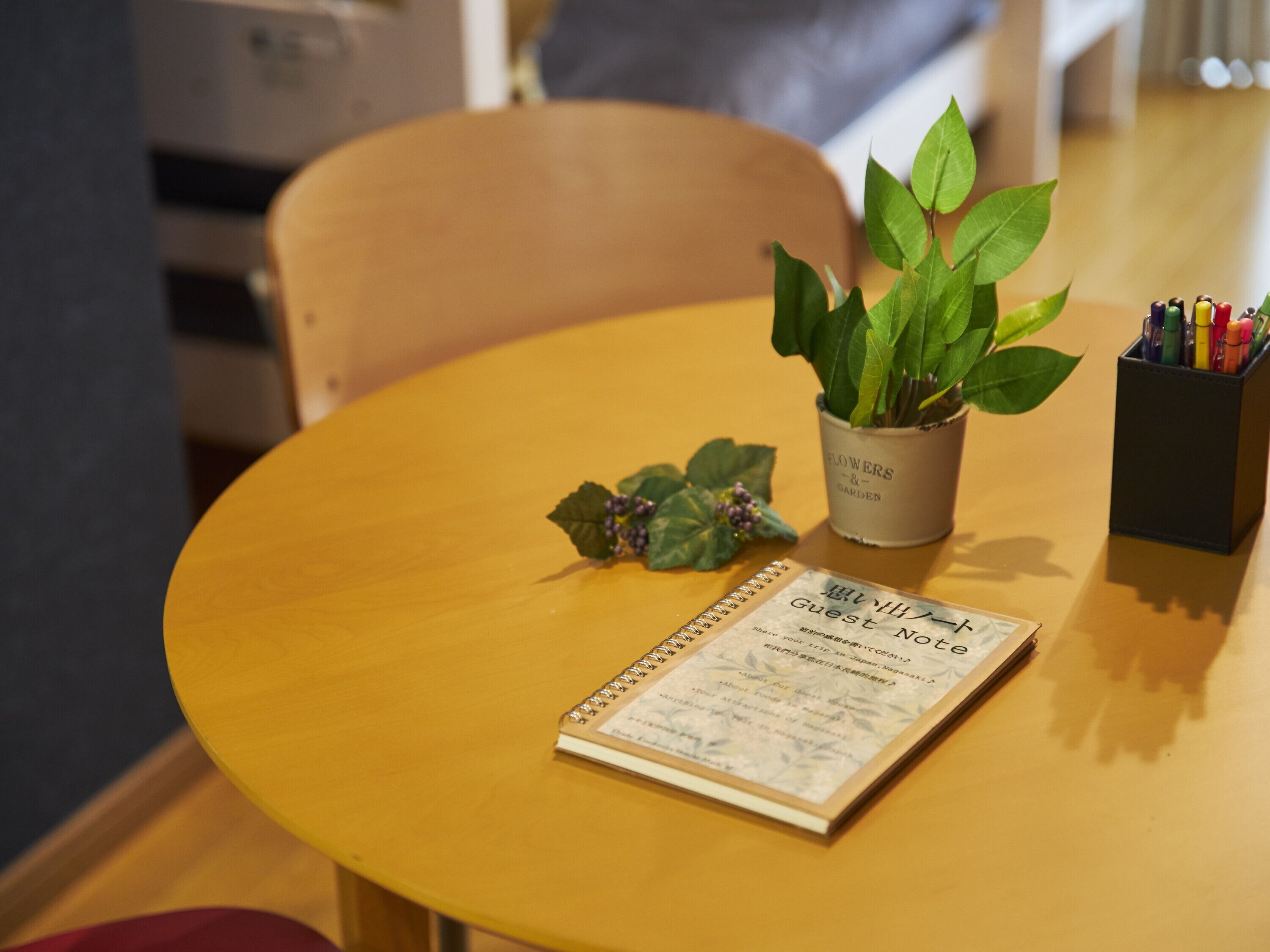A small round table with a spiral notebook labeled "Guest Note" and a potted plant.