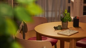 A round wooden table with a potted plant, a notebook, and a pen holder. - Oyado Kinokuniya Shinchi Machi (Nagasaki)