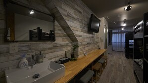 A modern kitchen with a wooden countertop, a sink, and a built-in stove. - Oyado Kinokuniya Shinchi Machi (Nagasaki)