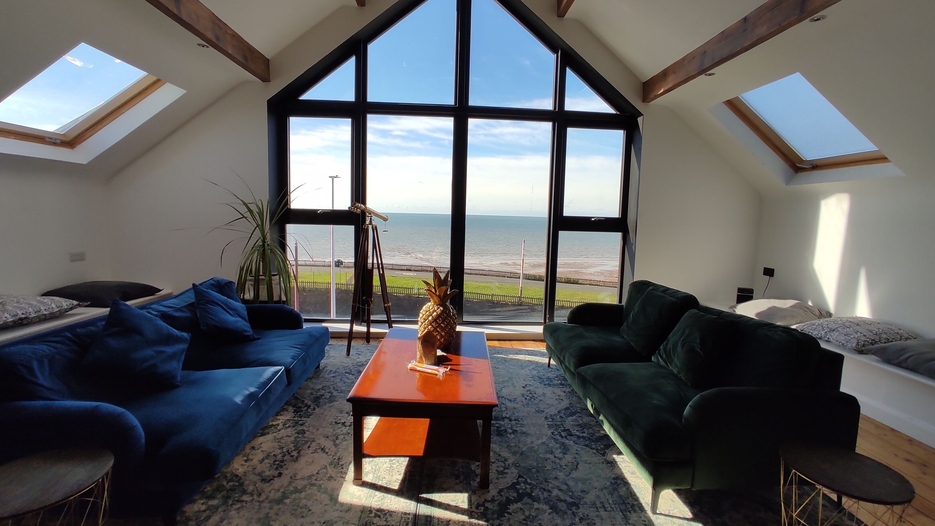 Ein geräumiges Loft mit hohen Decken, großen Fenstern und Meerblick sowie zwei gegenüberliegende Sofas.