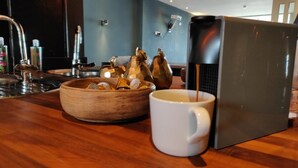 En kaffemaskin som fyller en vit mugg med kaffe, en träskål med mynt och ett diskho.