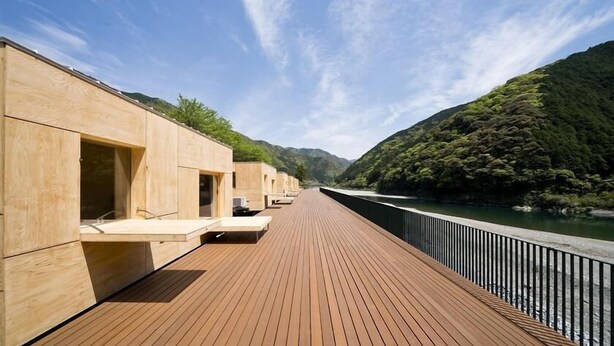 Une terrasse en bois dotée de coins salon intégrés et offrant une vue sur la rivière.