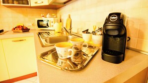 Eine Küchenarbeitsplatte mit Kaffeemaschine, zwei Tassen, einer Ablage und einer Mikrowelle.
