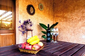 Een houten tafel met een rieten mand vol fruit, een fles wijn en twee glazen.