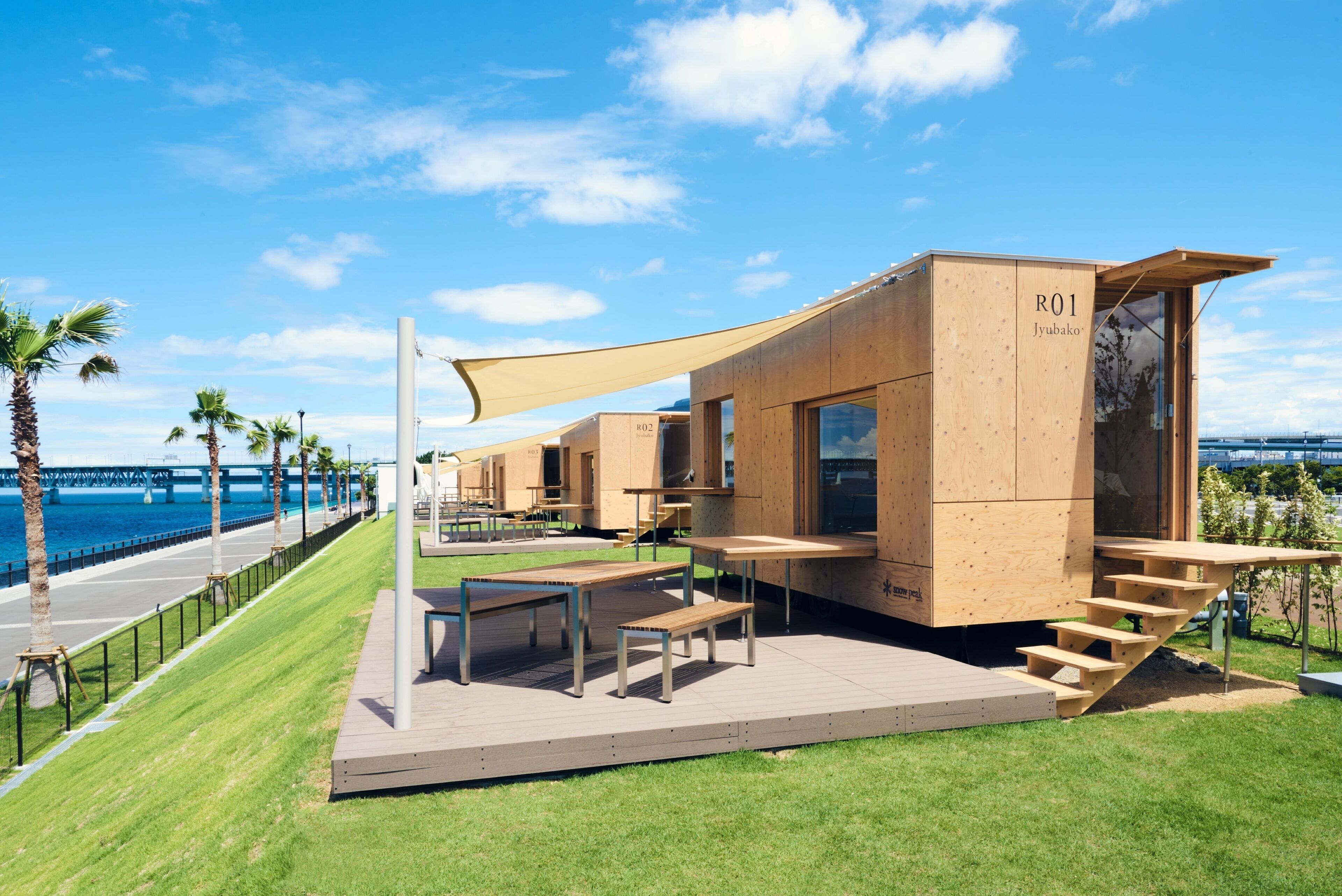 Una estructura moderna de madera con asientos al aire libre y vista al mar.