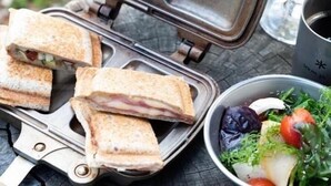 A sandwich maker with sandwiches and a salad bowl on a table. - Snow Peak Osaka Rinku (Izumisano)