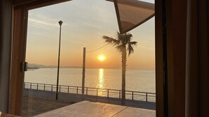 A view from a room with a large window overlooking a body of water at sunset. - Snow Peak Osaka Rinku (Izumisano)