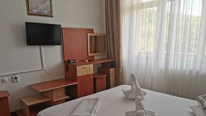 A hotel room with a bed, a TV mounted on the wall, a desk, and a window with curtains. - Hotel Ceres (Bala)