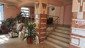 A lobby with a staircase, a reception desk, and a seating area with chairs and a sofa. - Hotel Ceres (Bala)