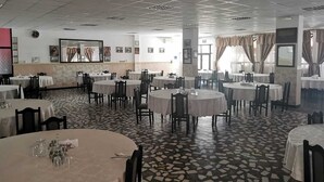 A spacious dining area with round tables and chairs, a patterned floor, and artwork on the walls. - Hotel Ceres (Bala)