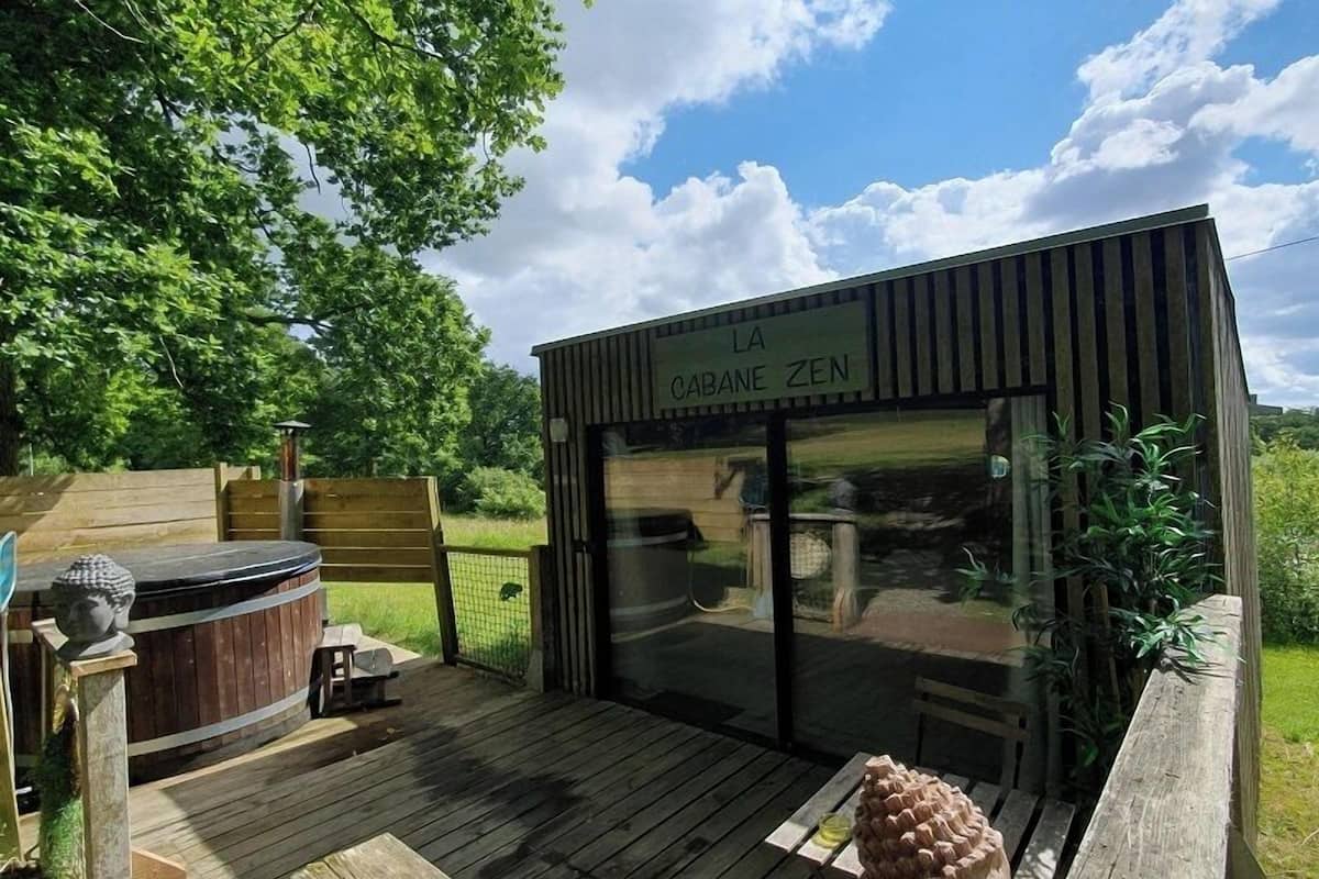 A wooden deck with a hot tub, benches, and a statue.