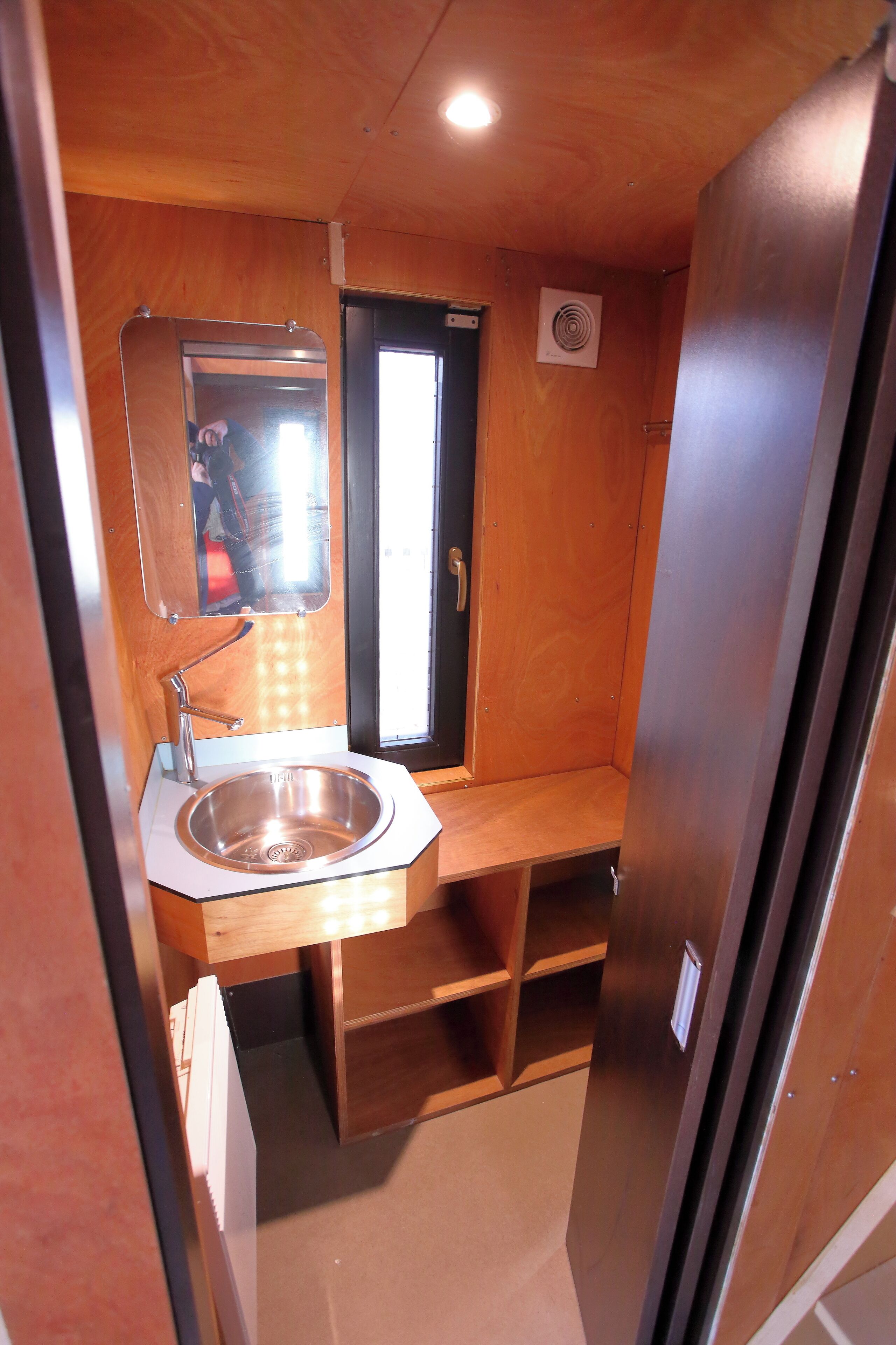 Een kleine badkamer met een wastafel, spiegel en raam.