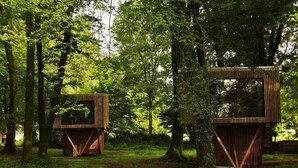 Two wooden treehouse structures in a forest. - Etape en forêt (Noues de Sienne)