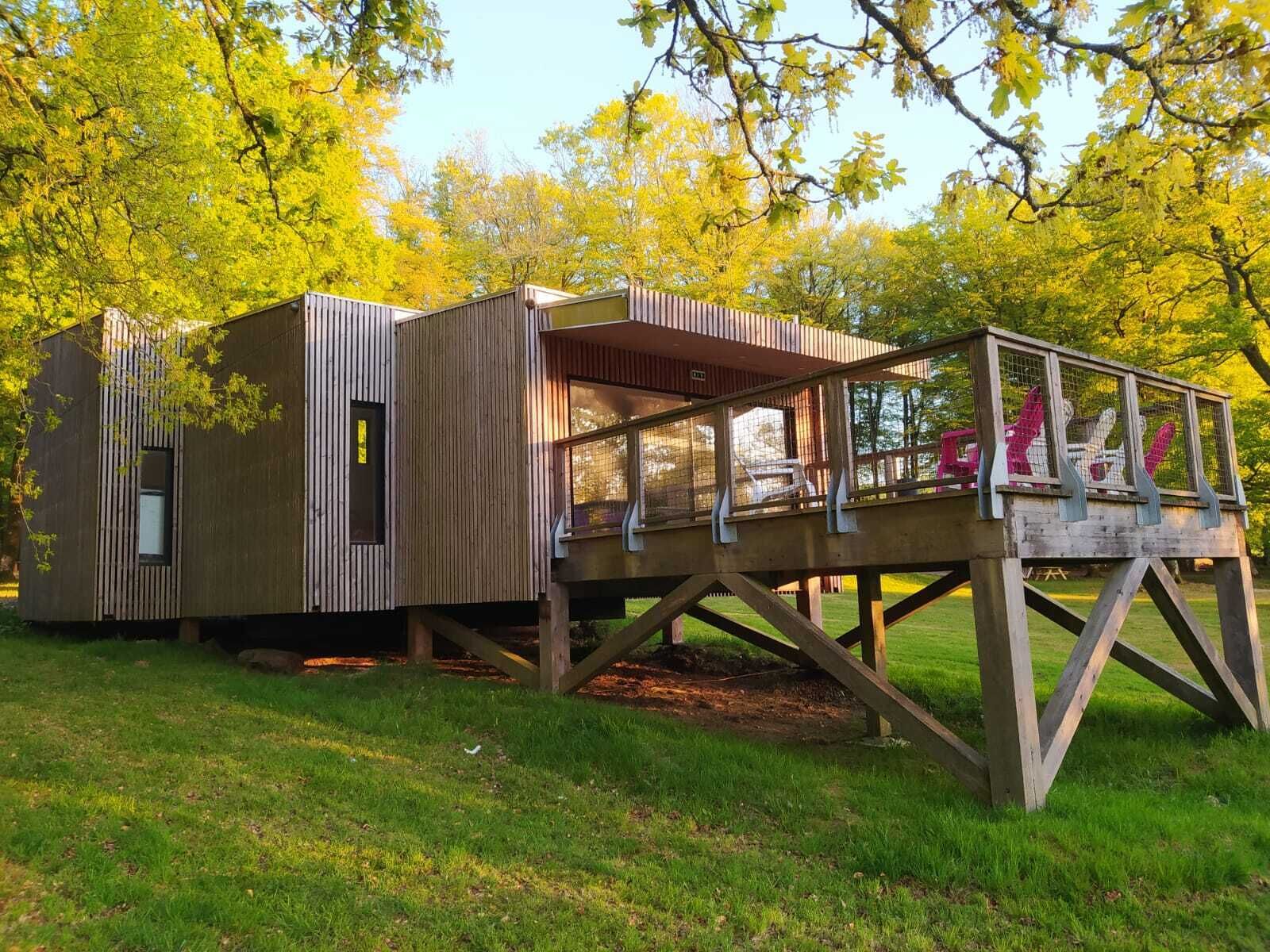 A wooden cabin with a deck and a fenced area.