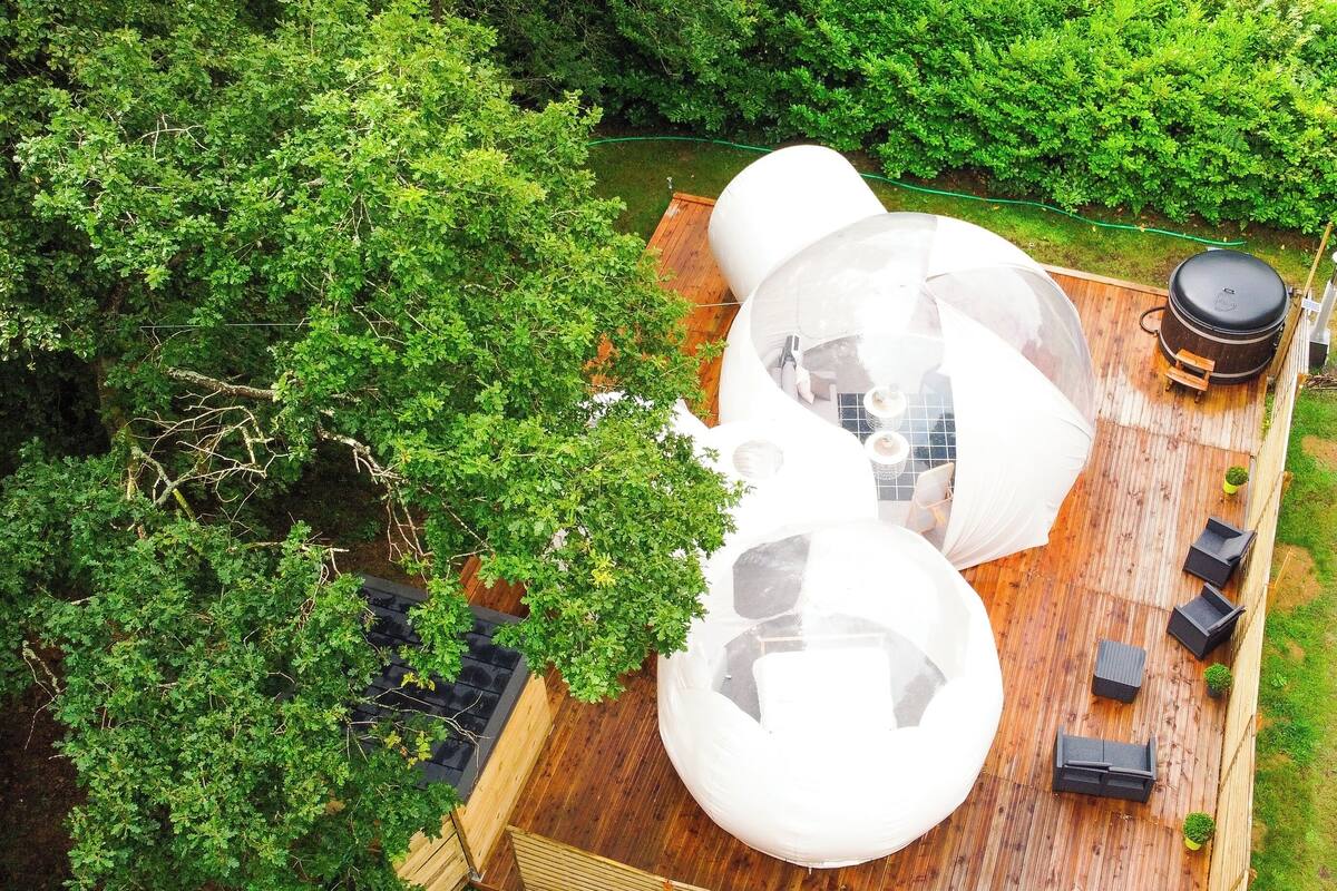 A wooden deck with transparent spherical structures, a wooden table, and seating.